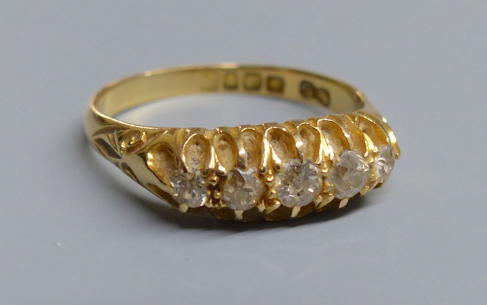 An Edwardian 18ct gold and graduated five stone diamond set half hoop ring, size P/Q, gross 4 grams.